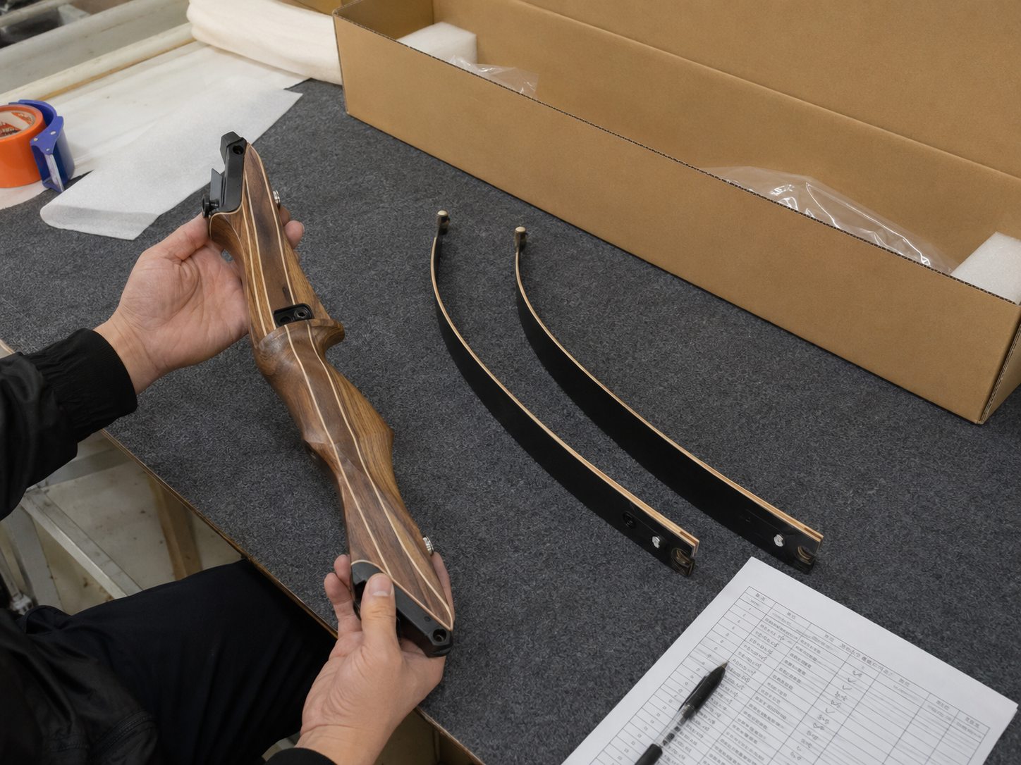 Hands inspecting recurve bow components before packing